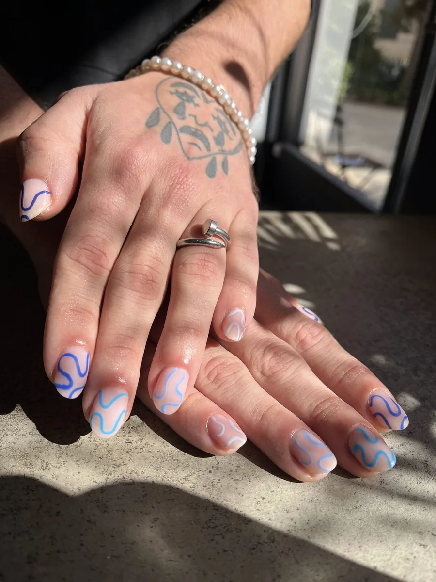 Short nude nails with wavy lines in shades of blue and white