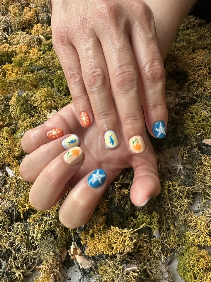 Uñas cortas de verano con soles, peces, naranjas y estrellas de mar